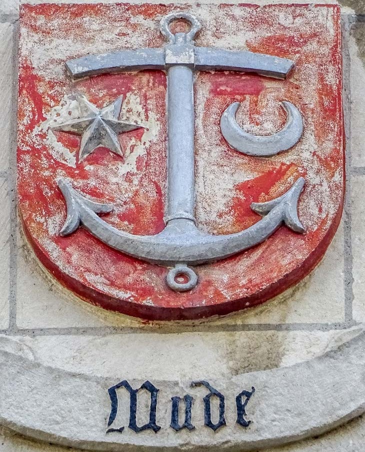 Rood wapenschild met een anker, ster en halve maan aan de gevel van het stadhuis van Brugge, met het woord Mude.
