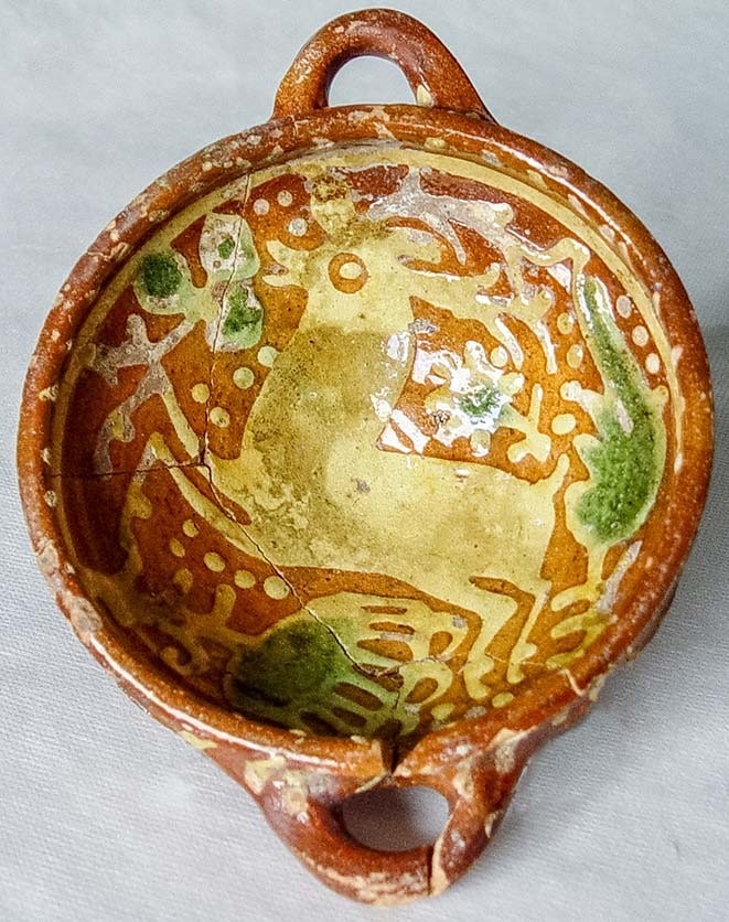 Kom met twee oren, van boven gezien, met een springend hert tussen bloemen in slibwerk.